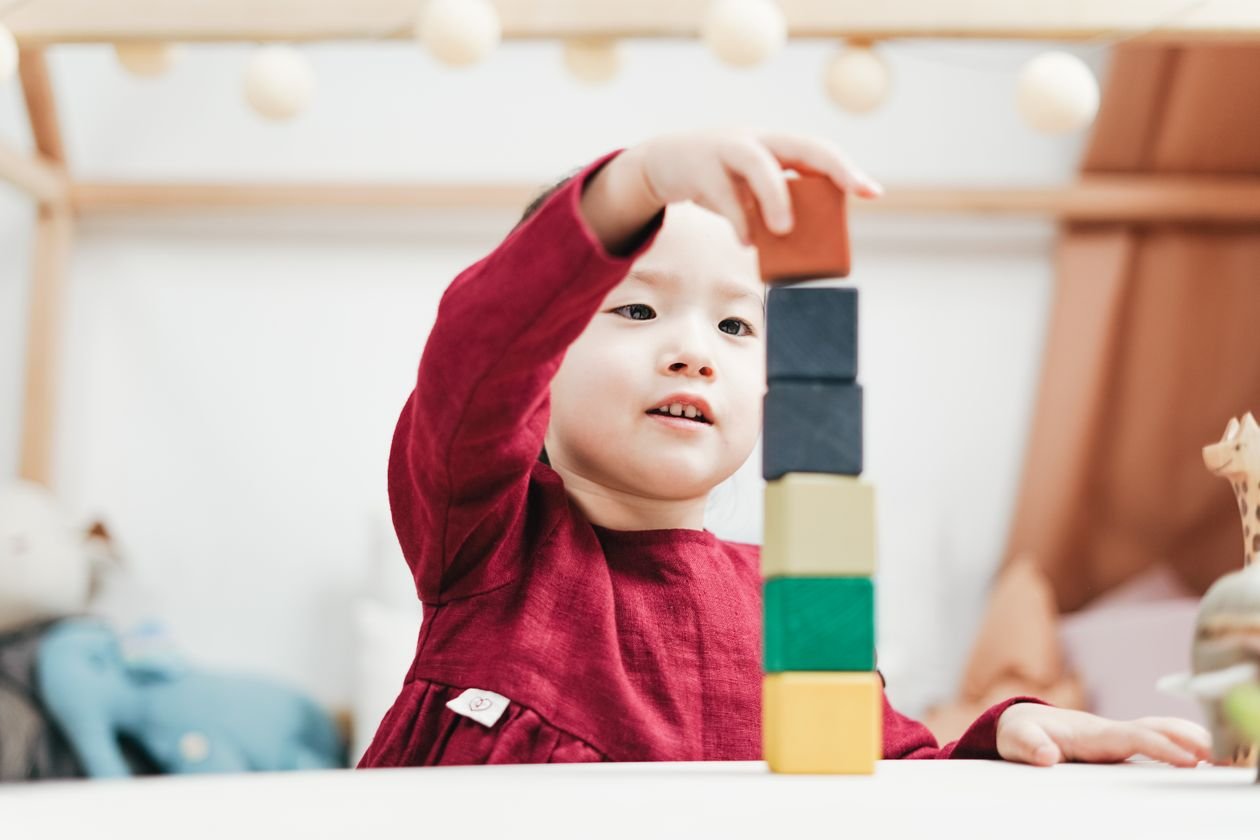 Young child building with colourful wooden blocks in a bright playroom